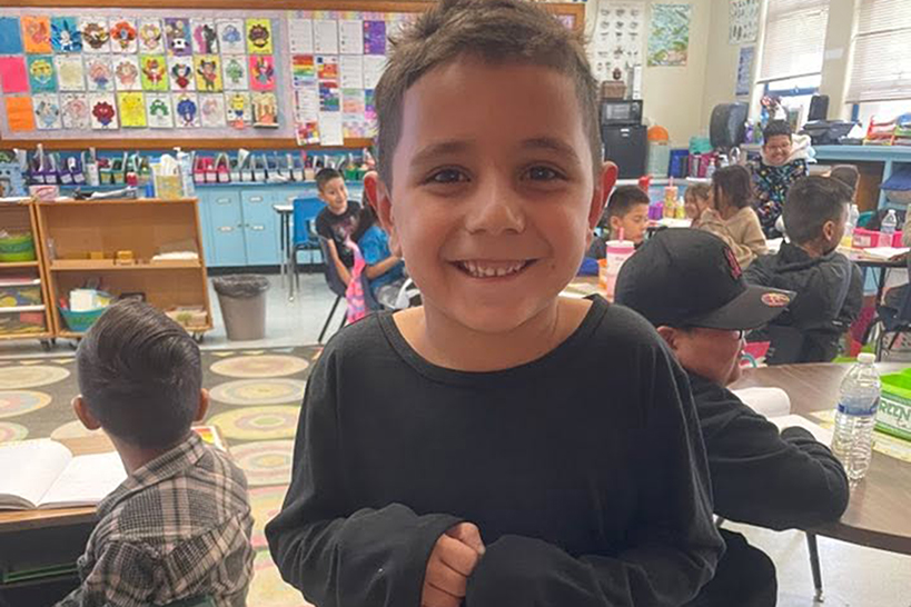 A little boy smiles holding a prize bag