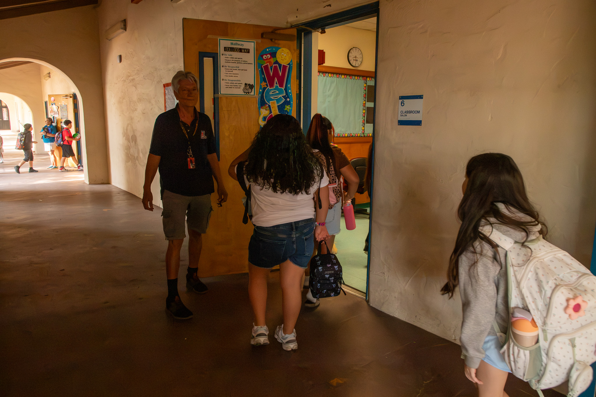 A teacher greets her students as they enter the classroom