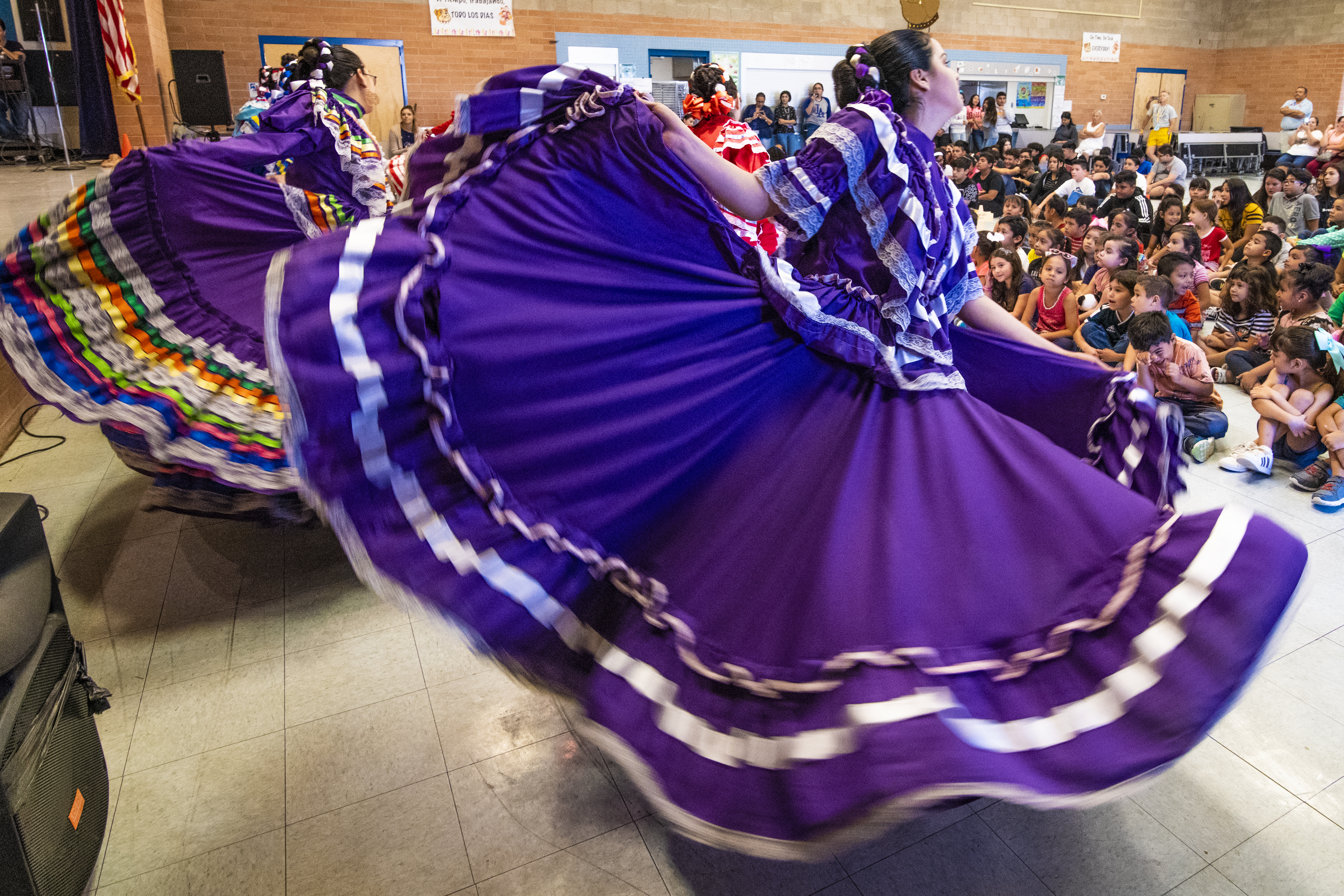 Folklorico dancers in purple dresses perform for students